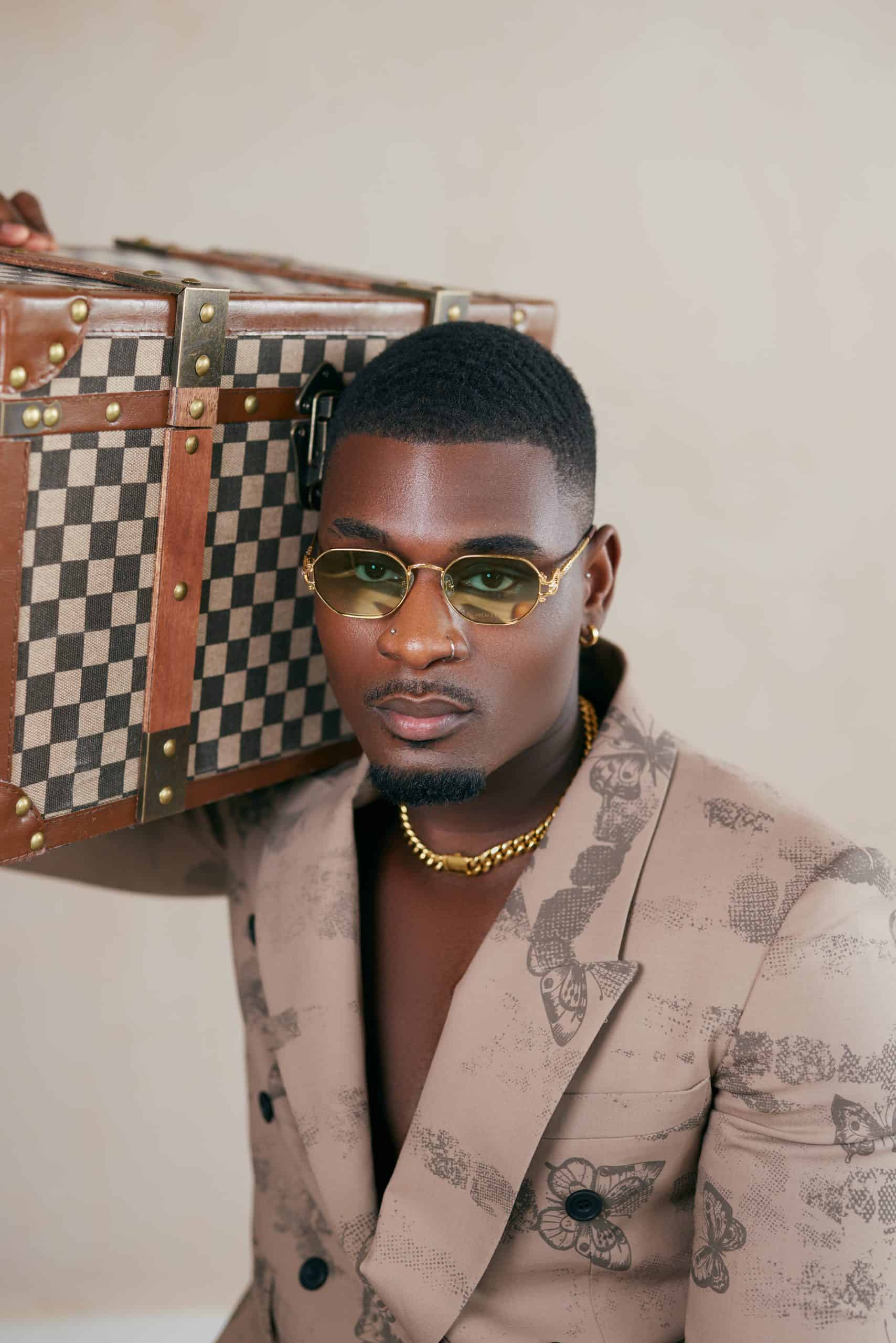 Man in sunglasses posing with checked luggage for a product and fashion shoot