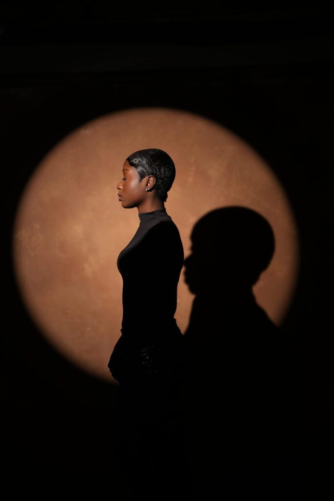 Silhouette portrait of a woman in profile against a spotlit brown backdrop